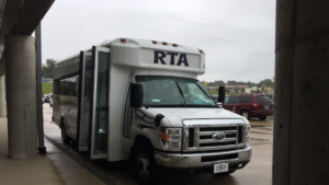 A white RTA accessible cutaway bus with its door open is parked under a covered walkway.