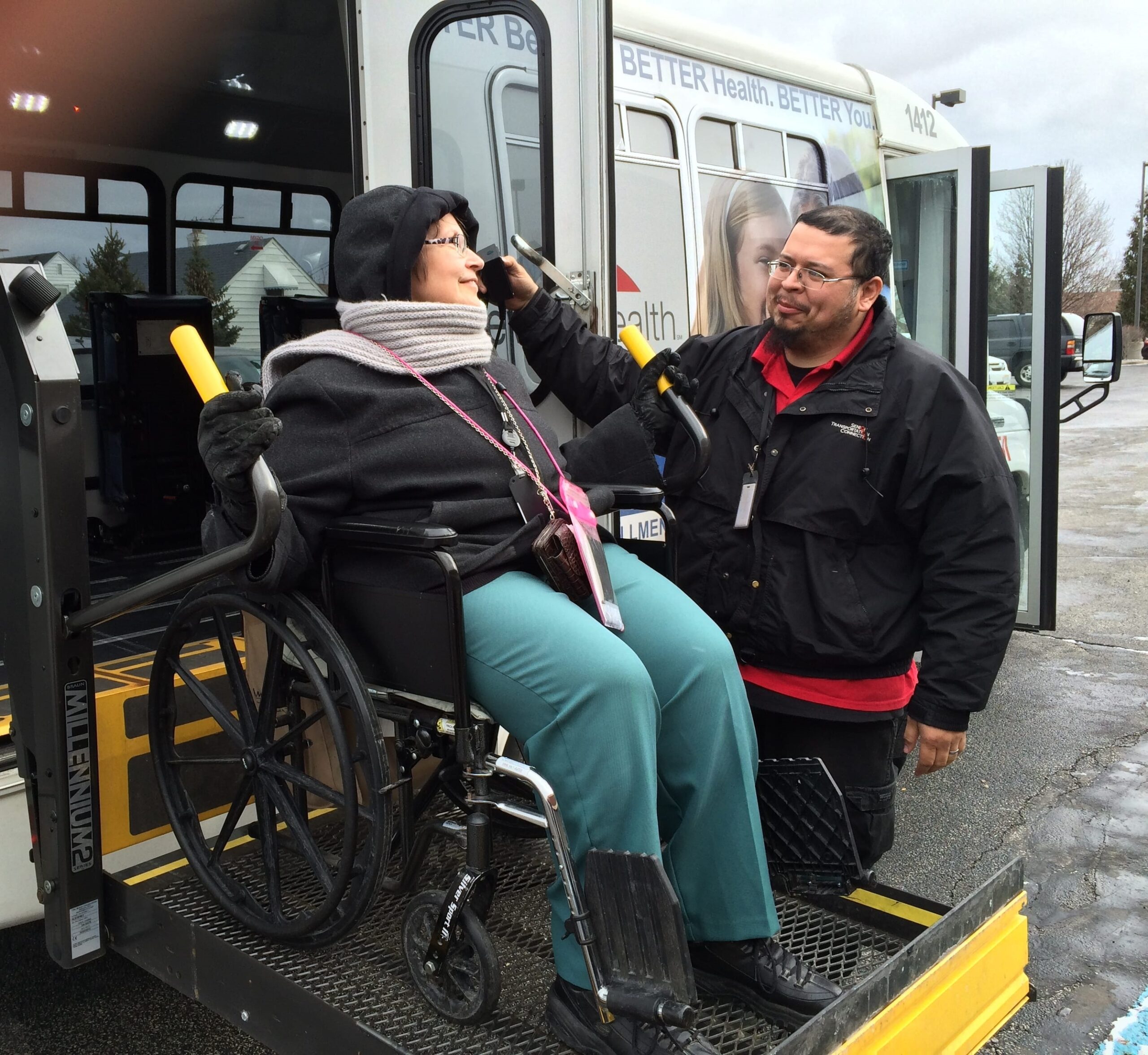 Driver assisting woman on wheelchair on lift