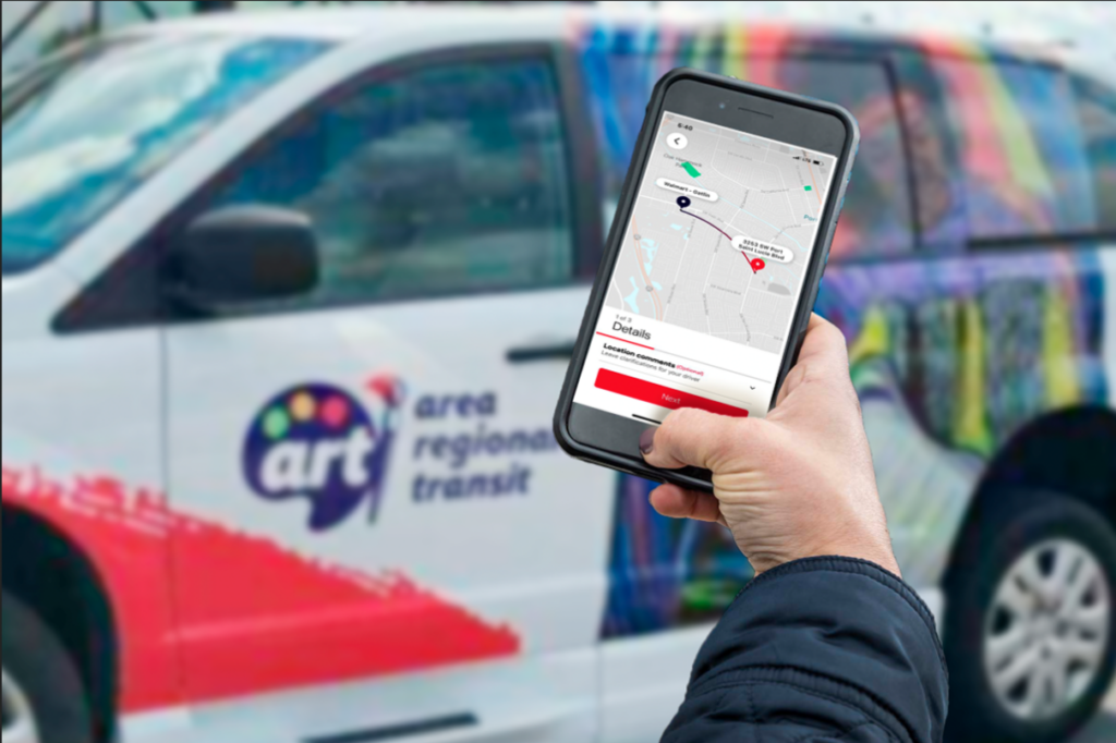 Image of person using app to book an ART On-Demand ride with ART On-Demand vehicle in background