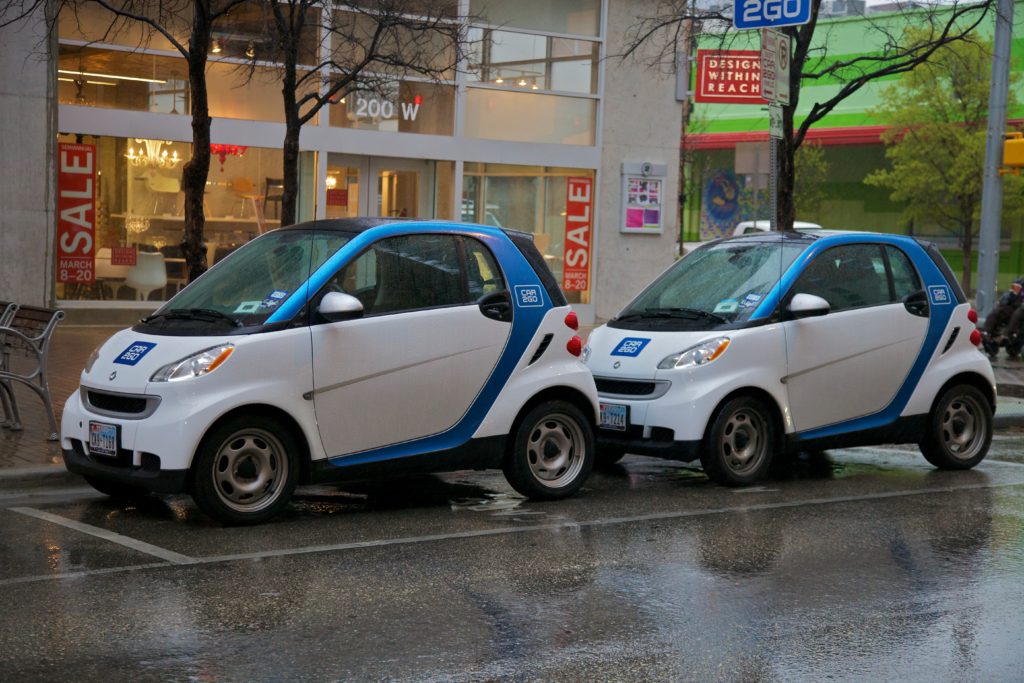 Two Car2Go cars parked on the street.