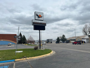 A sign on a grass median with the image of an eagle