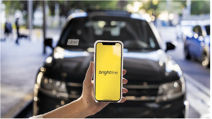 Image of person using Brightline app on smartphone in front of an Uber vehicle