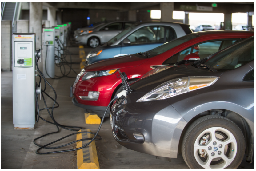 A picture of several electric vehicles charging in a garage.