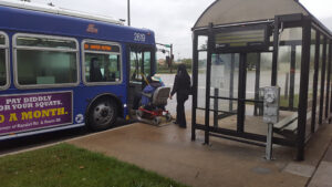 Driver assisting a man in a wheelchair entering the vehicle