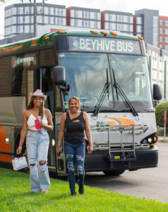 Two women in concert apparel outside of a bus. 