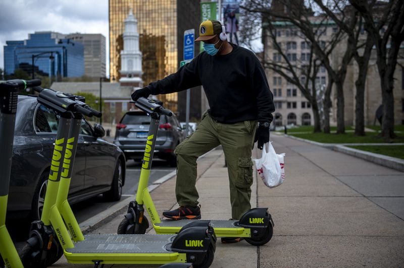Image of customer checking out LINK e-scooter in downtown Hartford