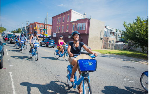 Several happy people riding Indego bikes in the street