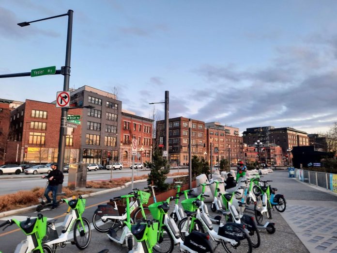 A cluster of dockless bikes and scooters on a sidewalk
