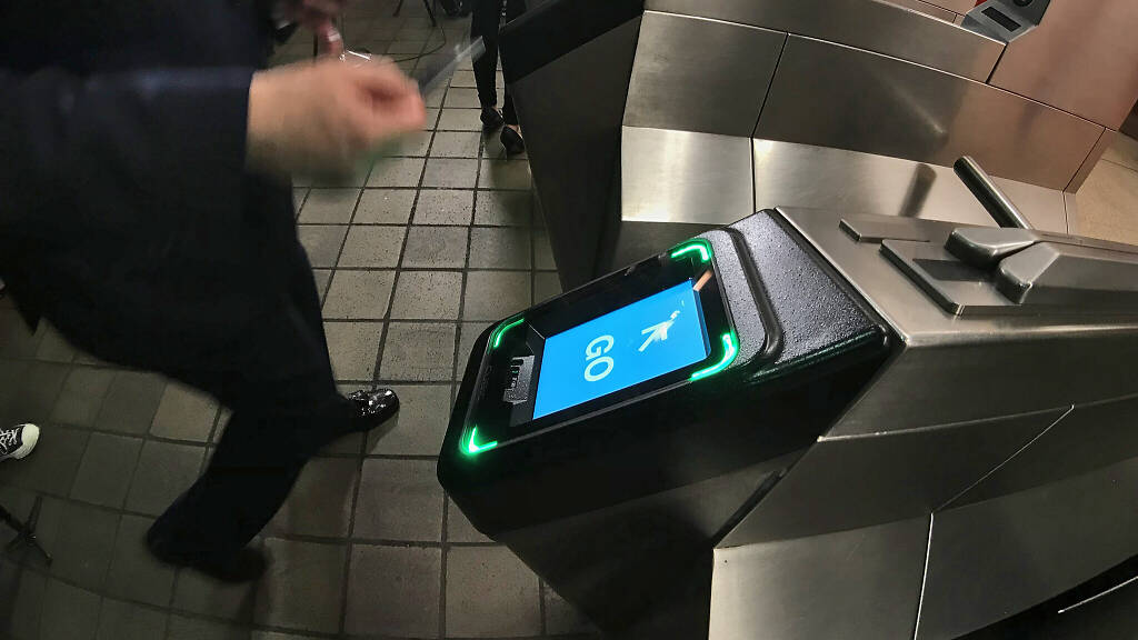 Image of man tapping his card as he enters an MTA subway station
