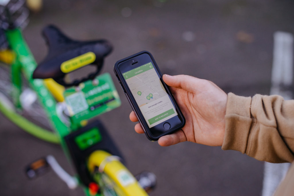 Photo of the bikeshare app and dockless bikeshare bicycle