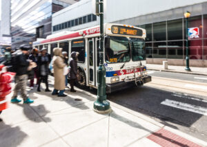 A bus pulling up to a busy stop. 