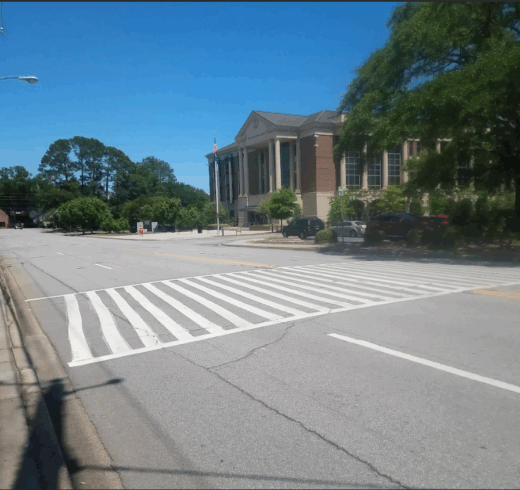 A road in the foreground with a painted crosswalk and a building in the background
