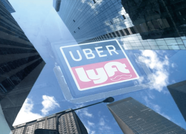 Uber & Lyft sticker on car with skyscrapers reflected on windshield