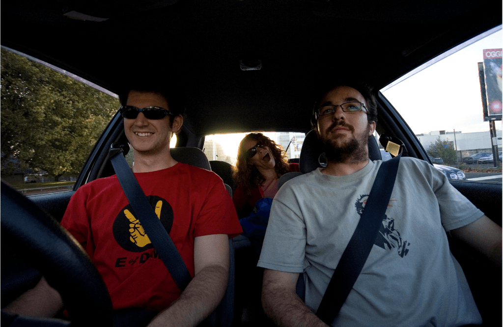 Photo of three people smiling and riding in a car