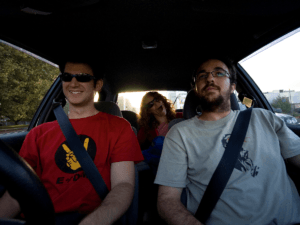 Photo of three people smiling and riding in a car