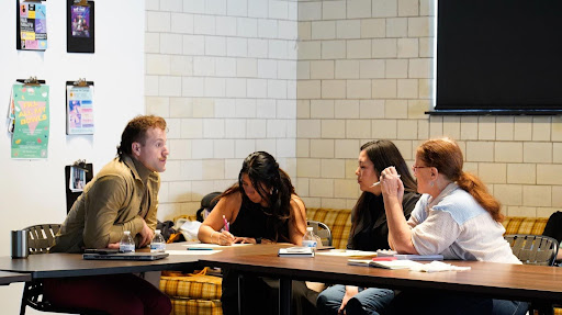 four people sit around a table talking