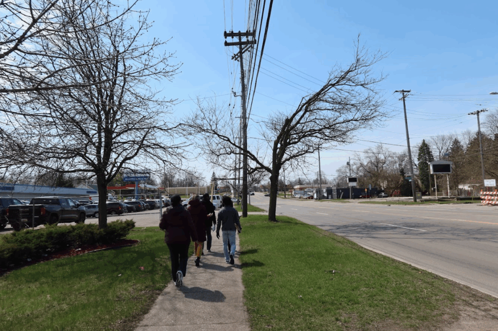 Several people walk away from the camera on a sidewalk