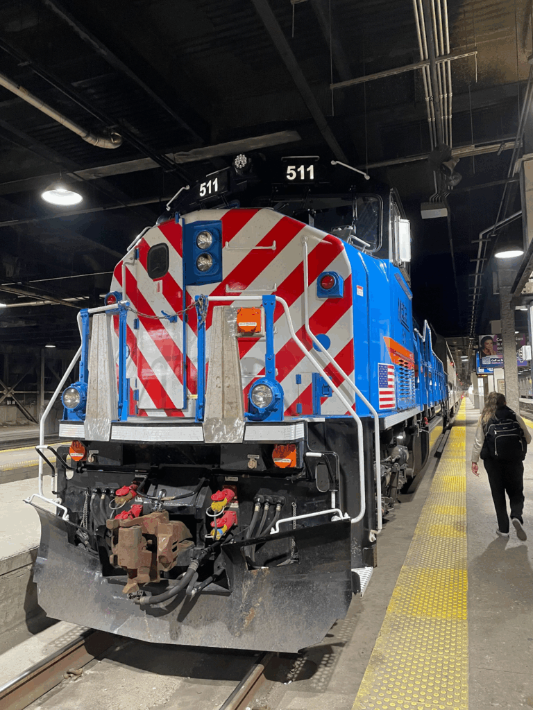 A blue, red, and white train facing the camera stopped at a platform