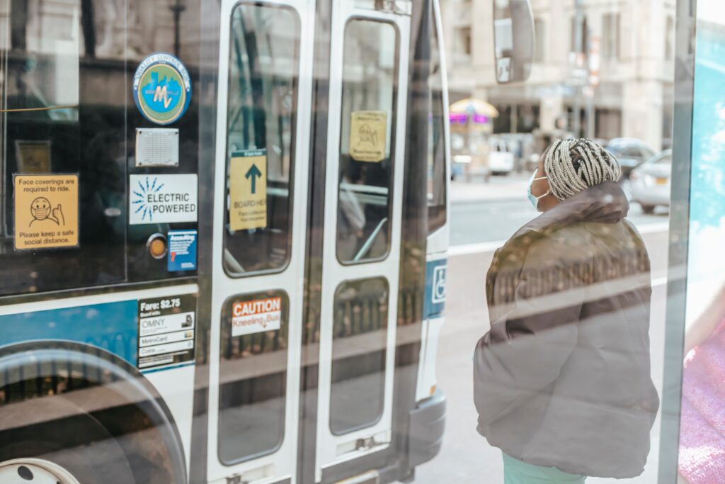 Woman wearing mask waits at bus stop