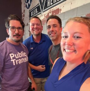 Four people smile at the camera