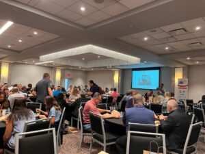 many people sit at tables in a large room