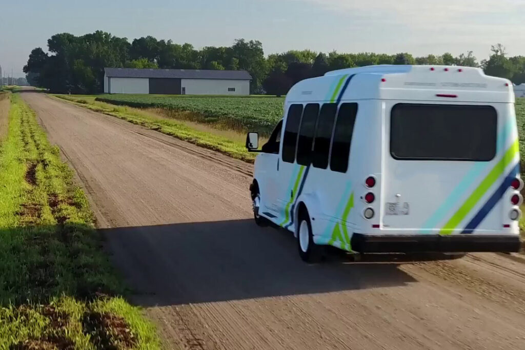 a white bus travels along a dirt road