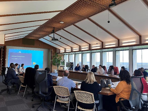 many people sit around tables and look at a presentation at the front of the room