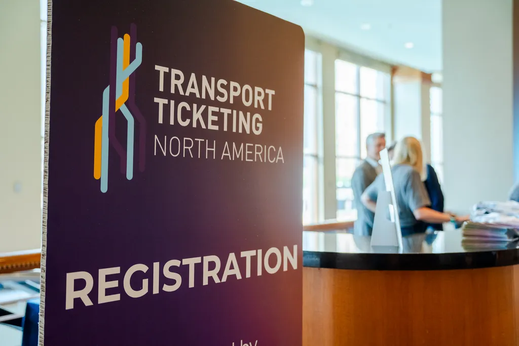 a banner reading "Transport Ticketing North America" and "Registration" next to a desk with two people behind it